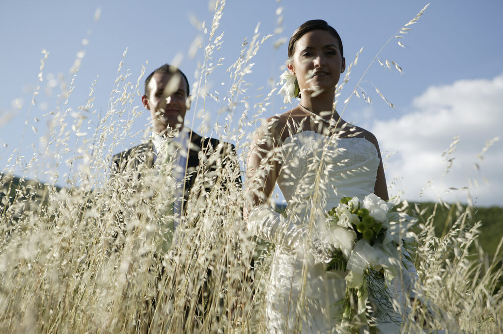 Bride and groom walking through tall grass on their wedding day