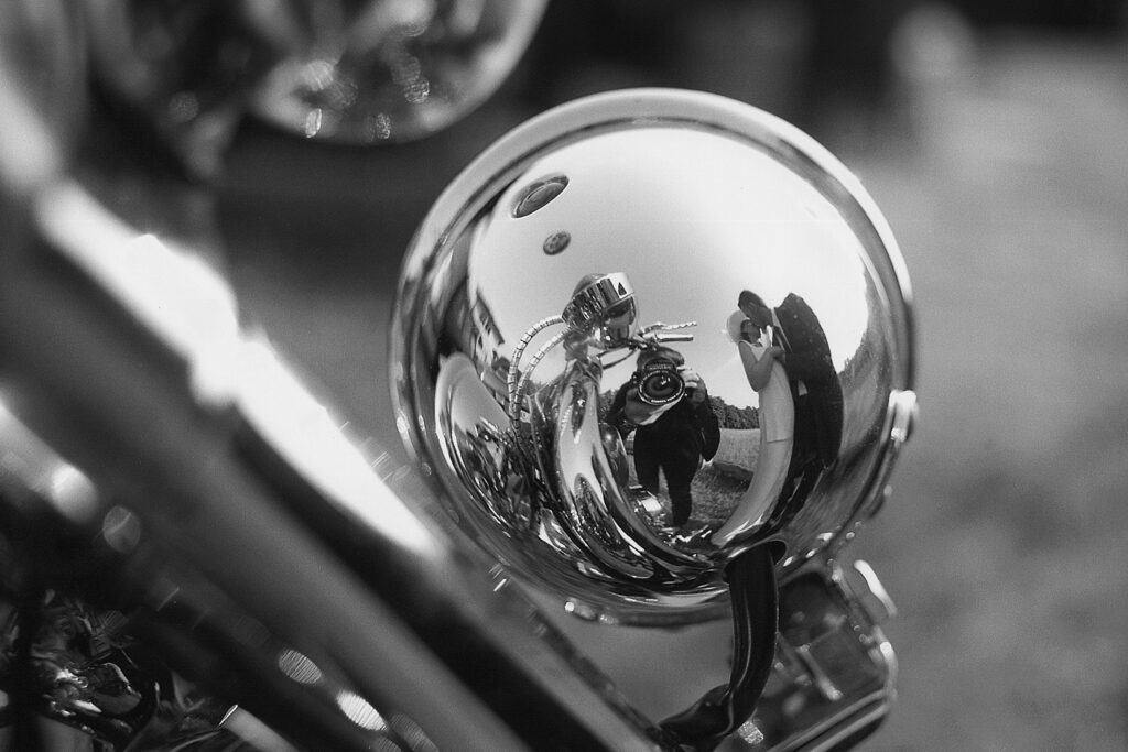 Bride and groom reflected in a motorcycle mirror during their wedding day