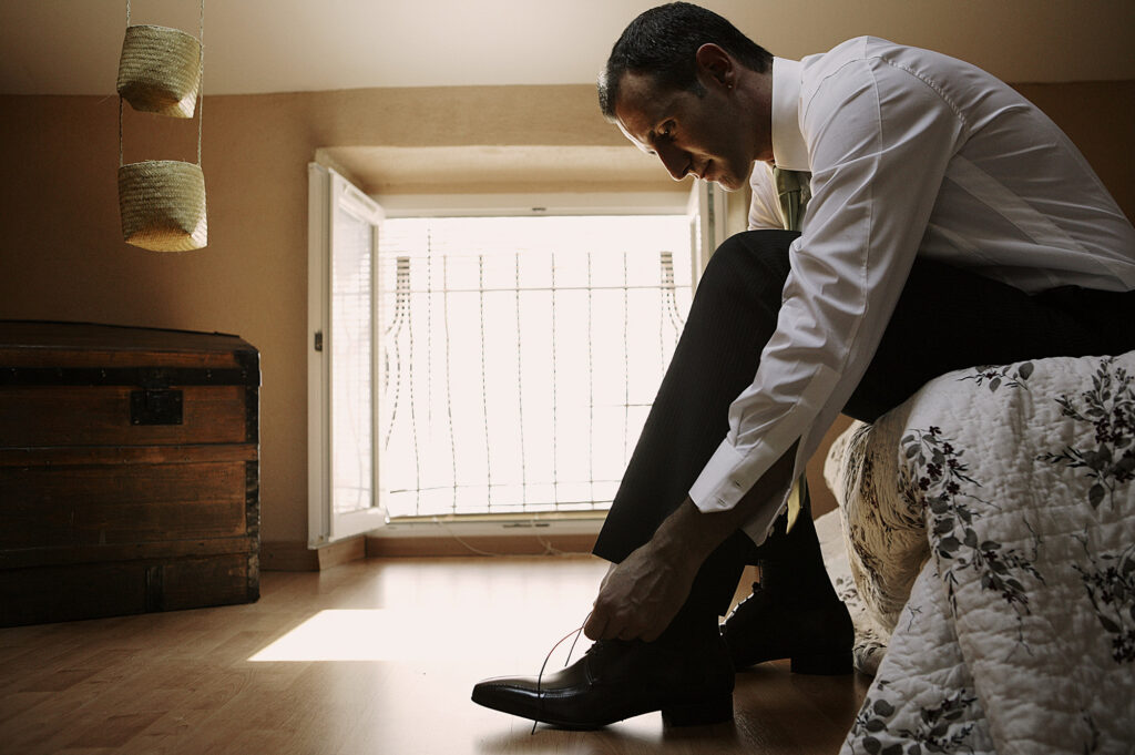 Groom putting on his shoes while getting ready for the wedding