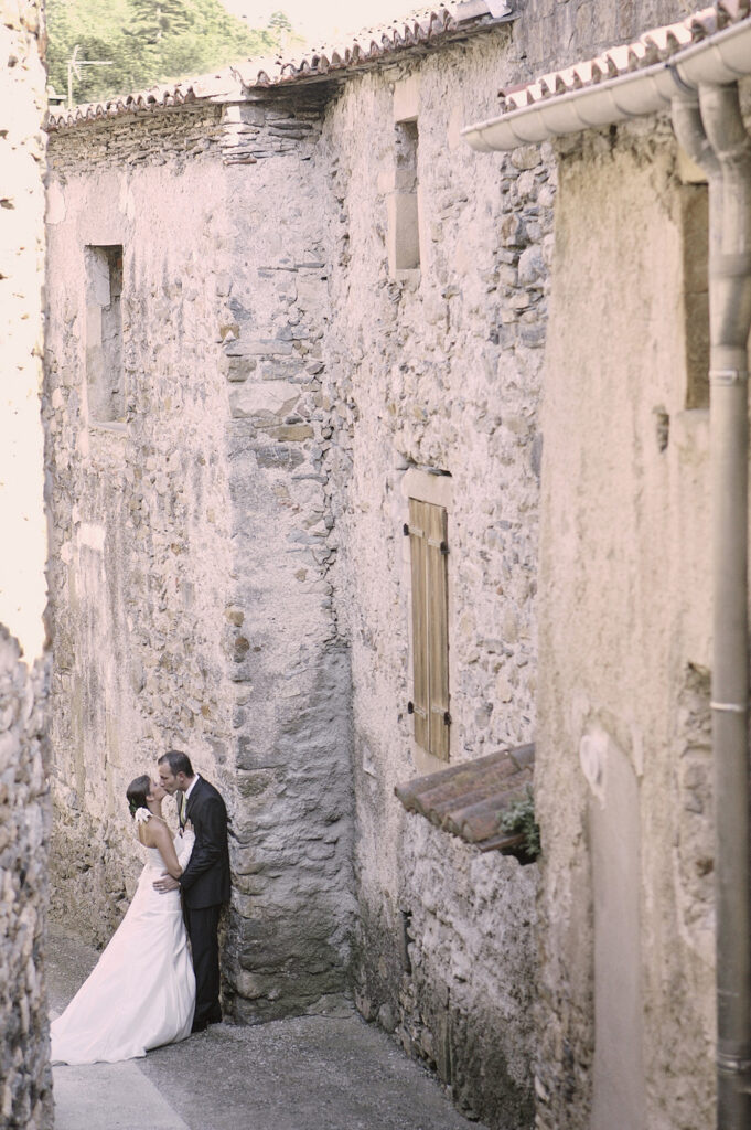 Bride and groom kissing in a narrow stone street on their wedding day