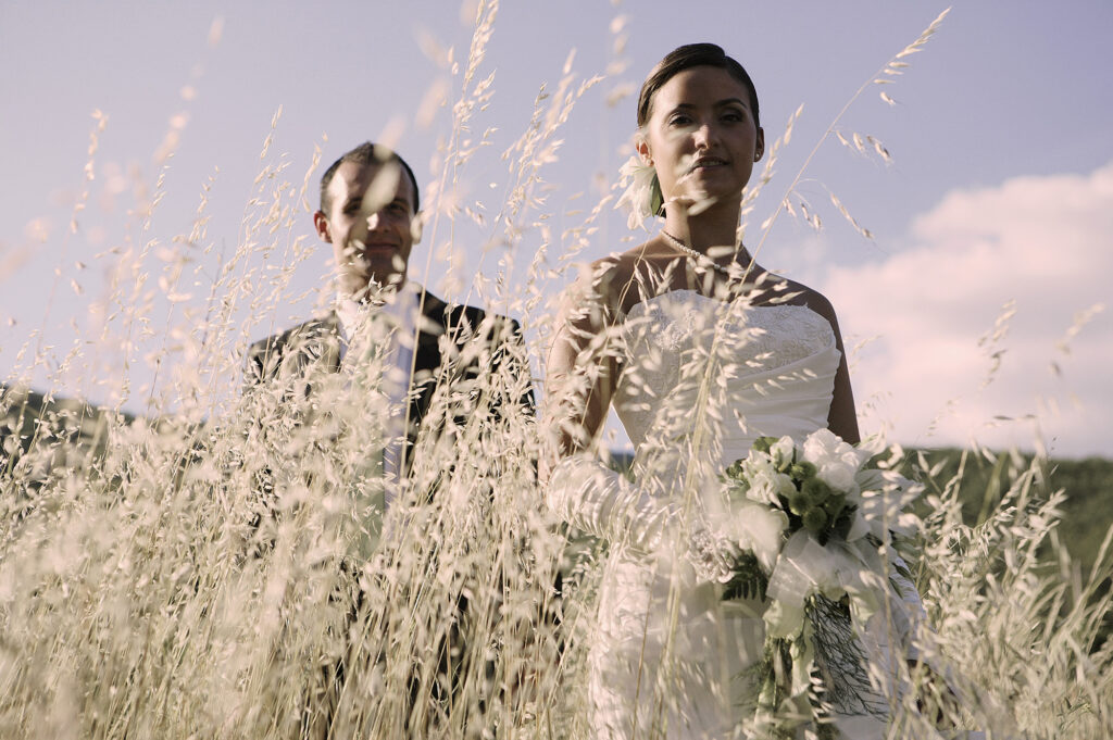 Bride and groom standing together in tall grass on their wedding day
