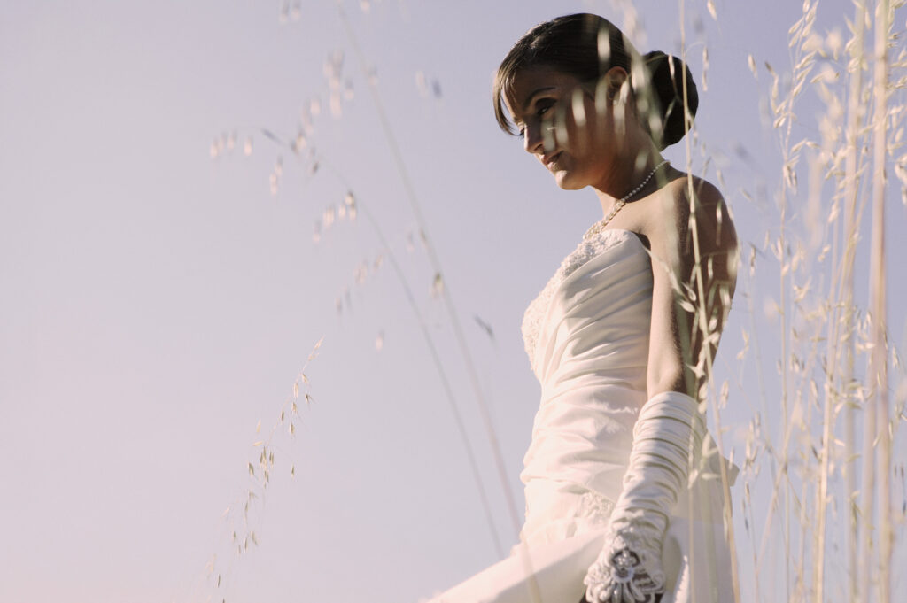 Bride standing in tall grass in soft natural light on her wedding day