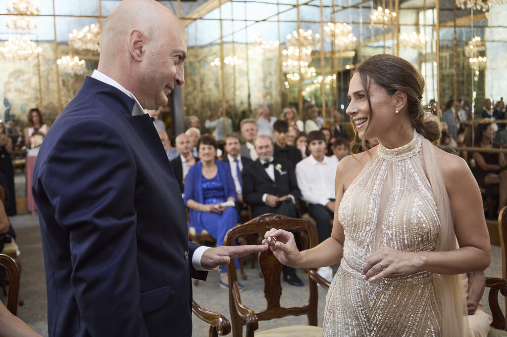 Bride placing the wedding ring on the groom's finger during the ceremony