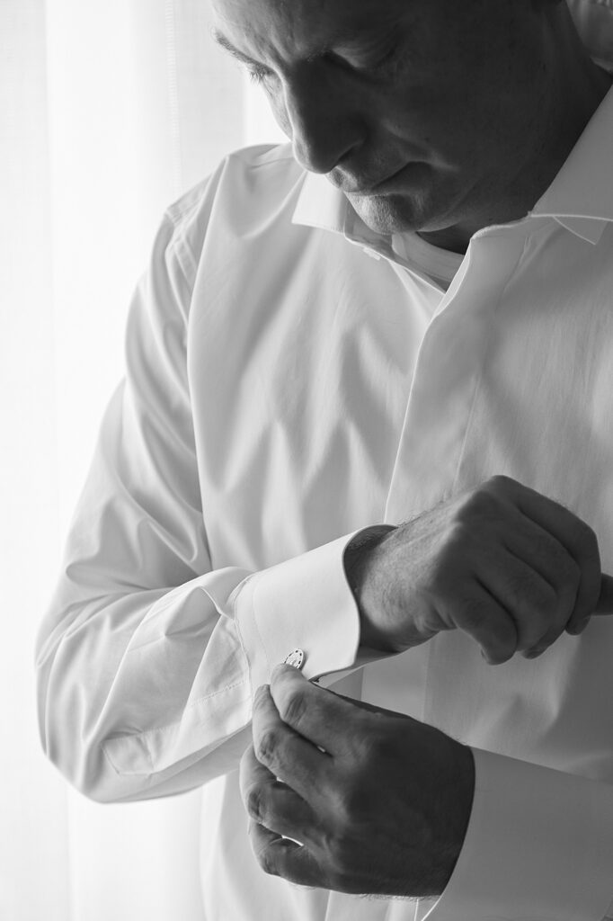 Groom fastening his cufflinks while getting ready for the wedding