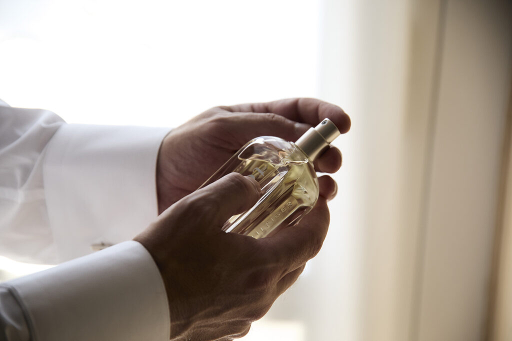 Groom applying perfume while getting ready for the wedding