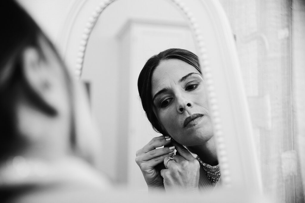 Bride putting on her earrings while getting ready for the wedding
