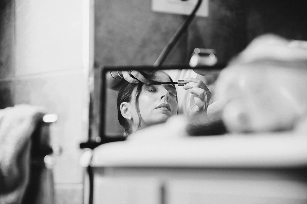 Bride having her makeup applied reflected in a mirror before the wedding