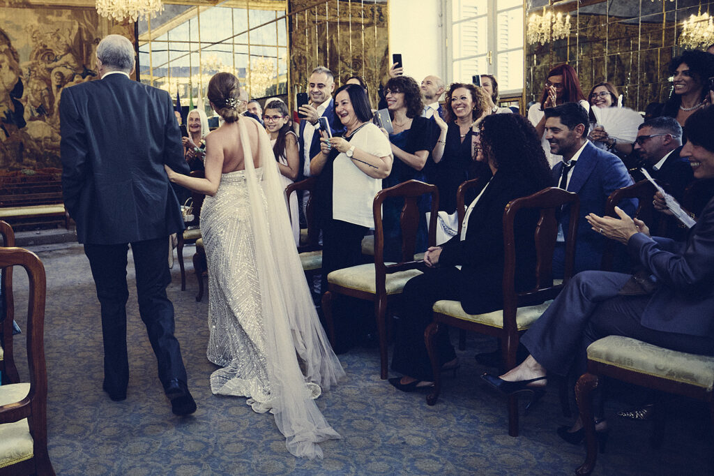 Bride walking down the aisle with her father as wedding guests look on