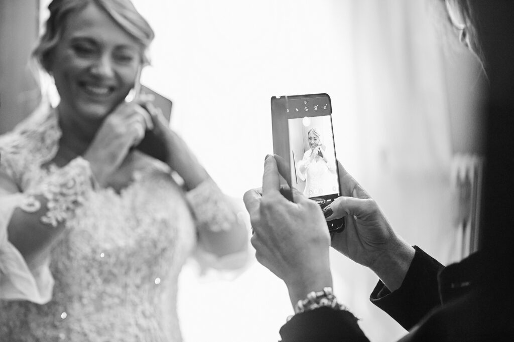 Bride getting ready while a friend takes her photo before the wedding