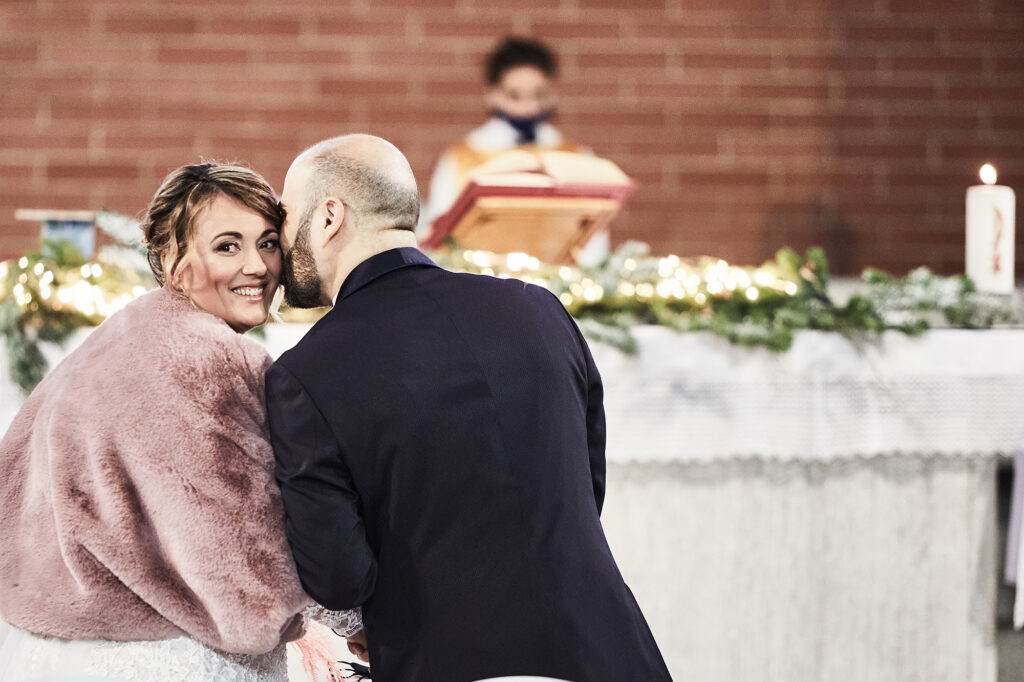 Bride smiling as the groom leans close during the wedding ceremony