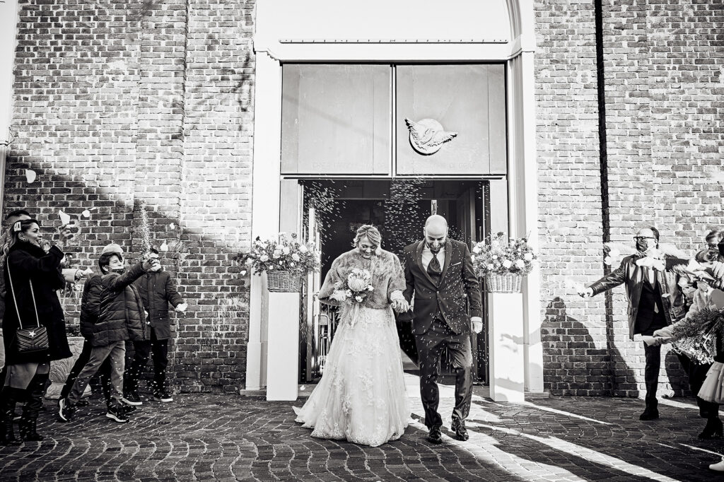 Bride and groom leaving the wedding ceremony as guests throw rice
