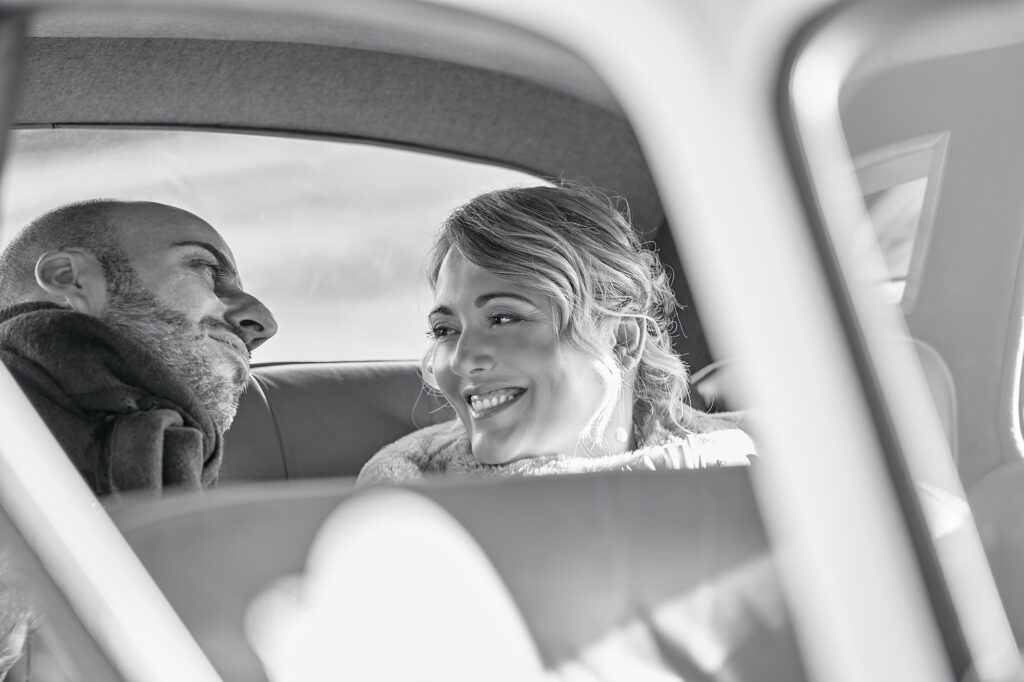 Bride and groom sharing a joyful moment in the wedding car